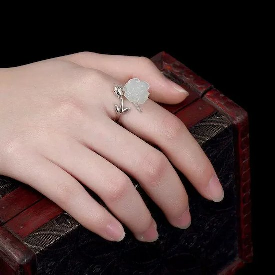 a hand model wearing a white rose jade ring with silver leaf