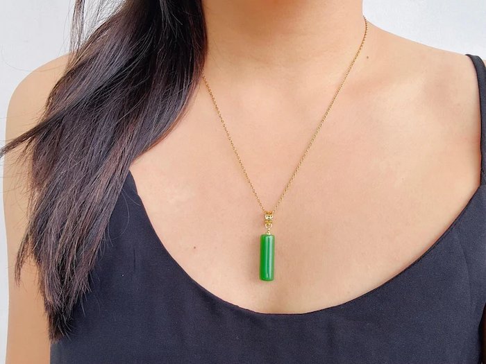 A model wearing a green jade tube pendant with 18k gold plated necklace