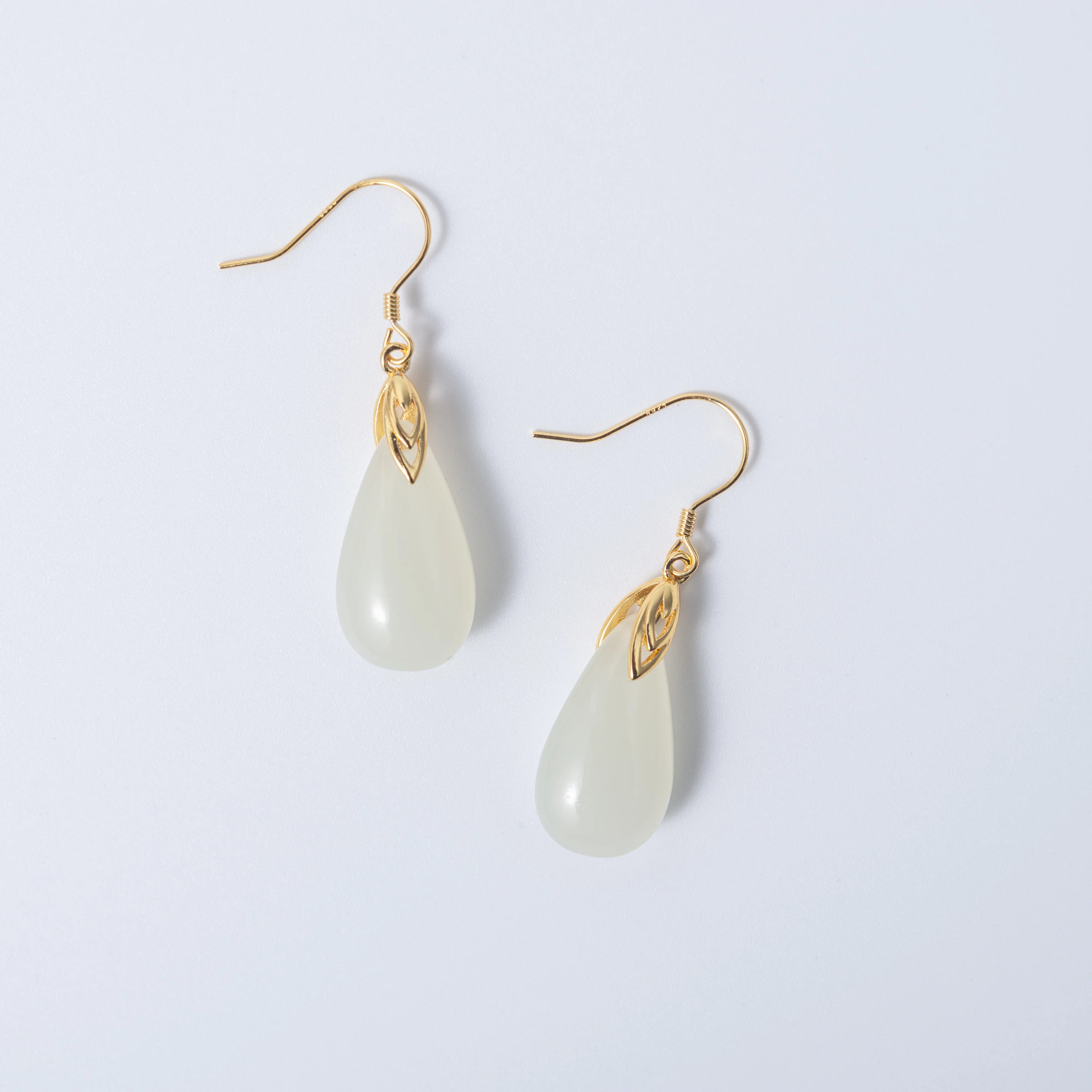 Modern white jade drop earrings in sleek gold design with teardrop silhouette on a white background