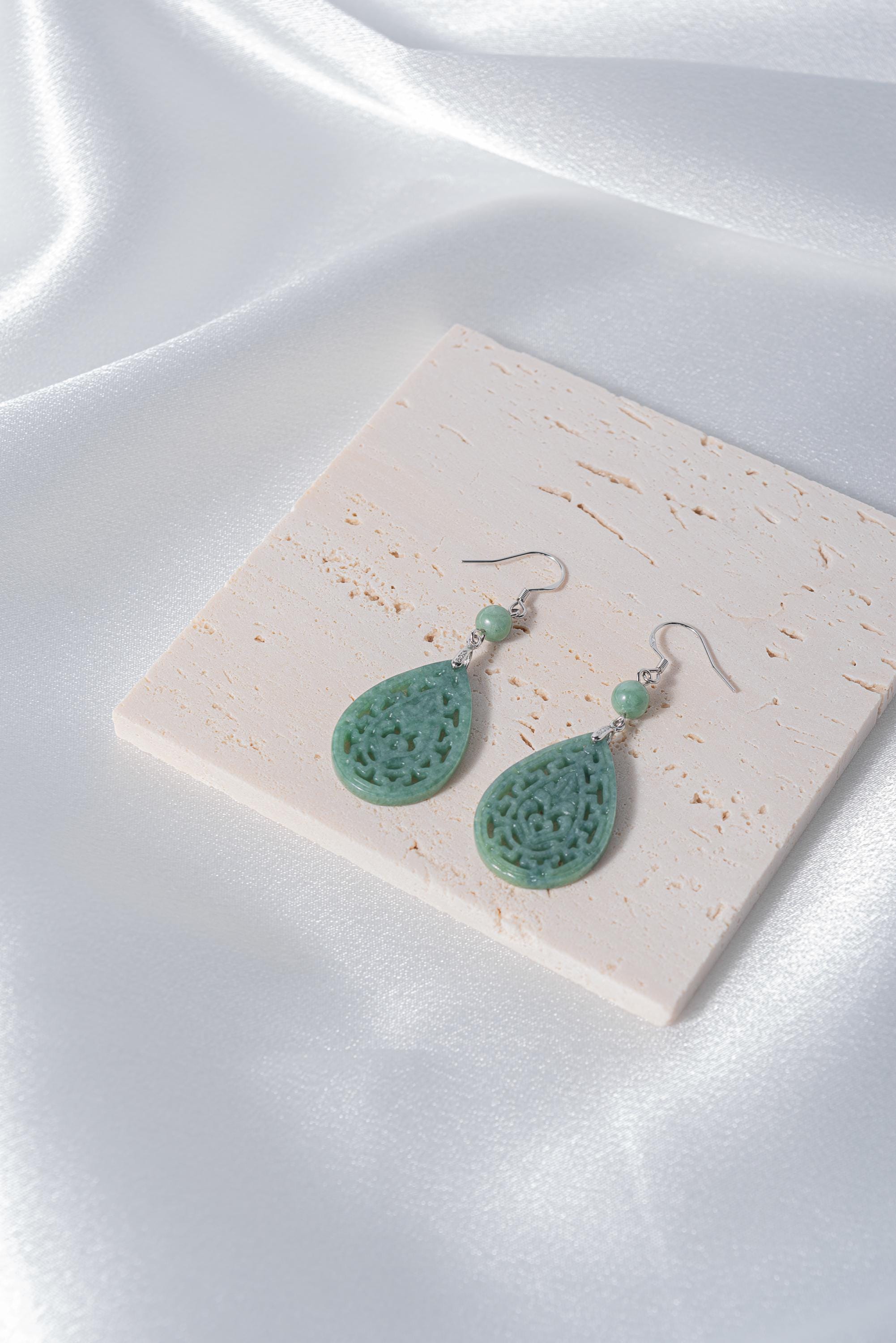 Side angle showing silver lace setting around light green jade teardrop stone