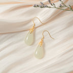 14k gold teardrop earrings with white jade center on a silk cloth