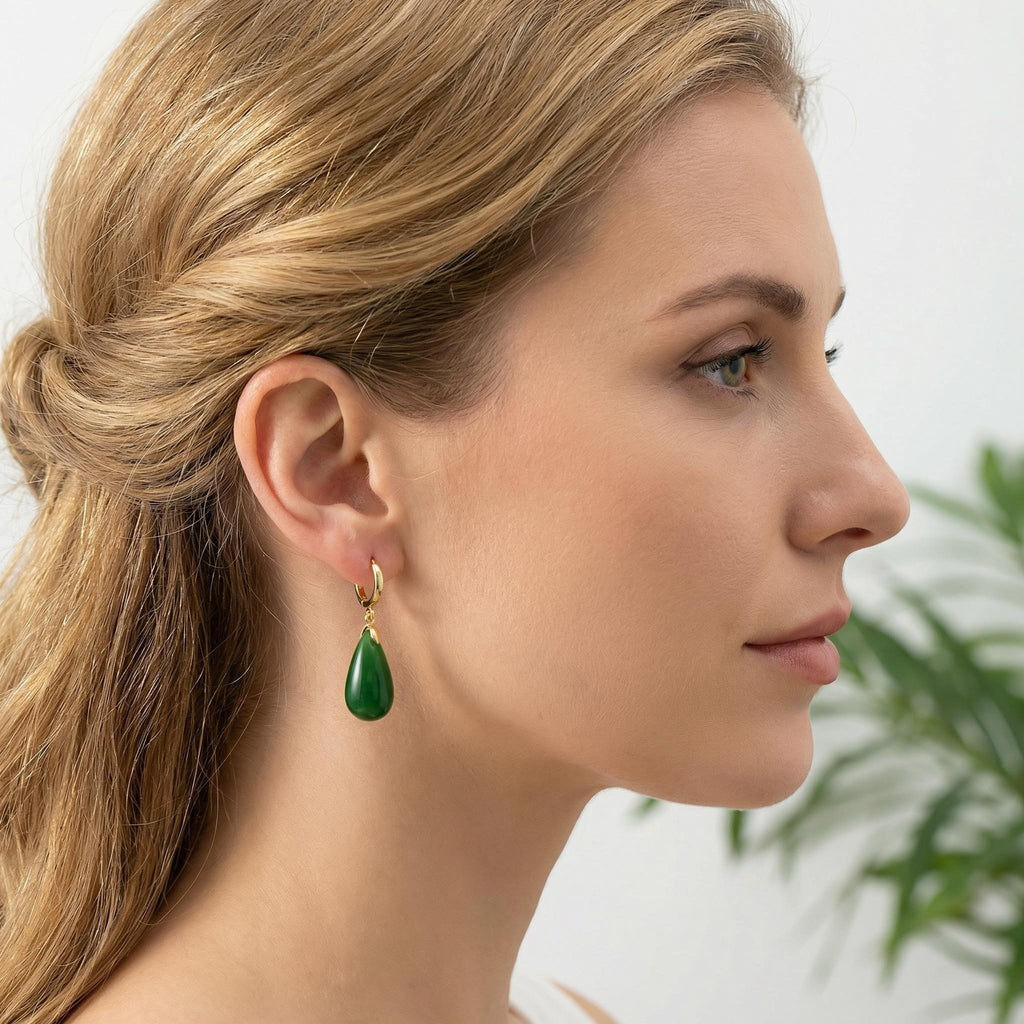 Close-up of a woman wearing green teardrop earrings with a blurred background