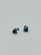Close-up of sterling silver snake eye earrings featuring blue topaz-inspired stone and textured setting