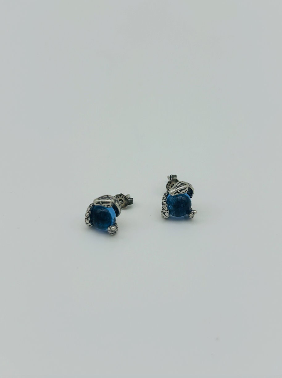 Close-up of sterling silver snake eye earrings featuring blue topaz-inspired stone and textured setting