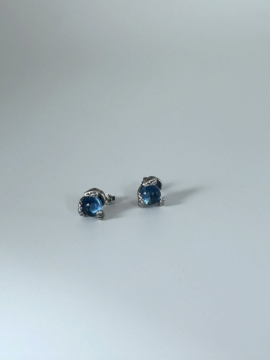 Front view of tiny snake eye stud earrings with blue gemstone set in sterling silver