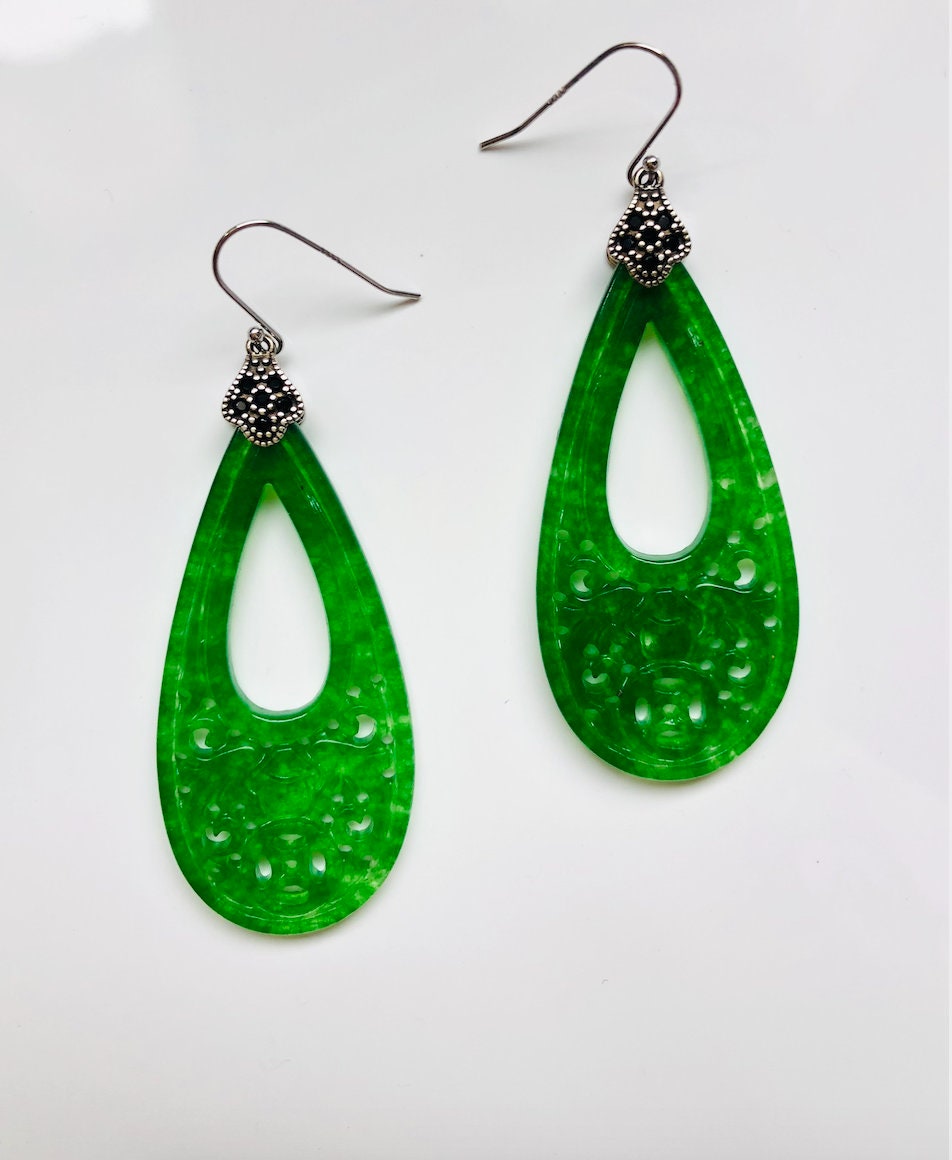Close-up of intricate carved jade teardrops with vintage silver setting

