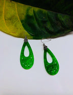 Carved jade and silver dangle earrings placed with a leaf