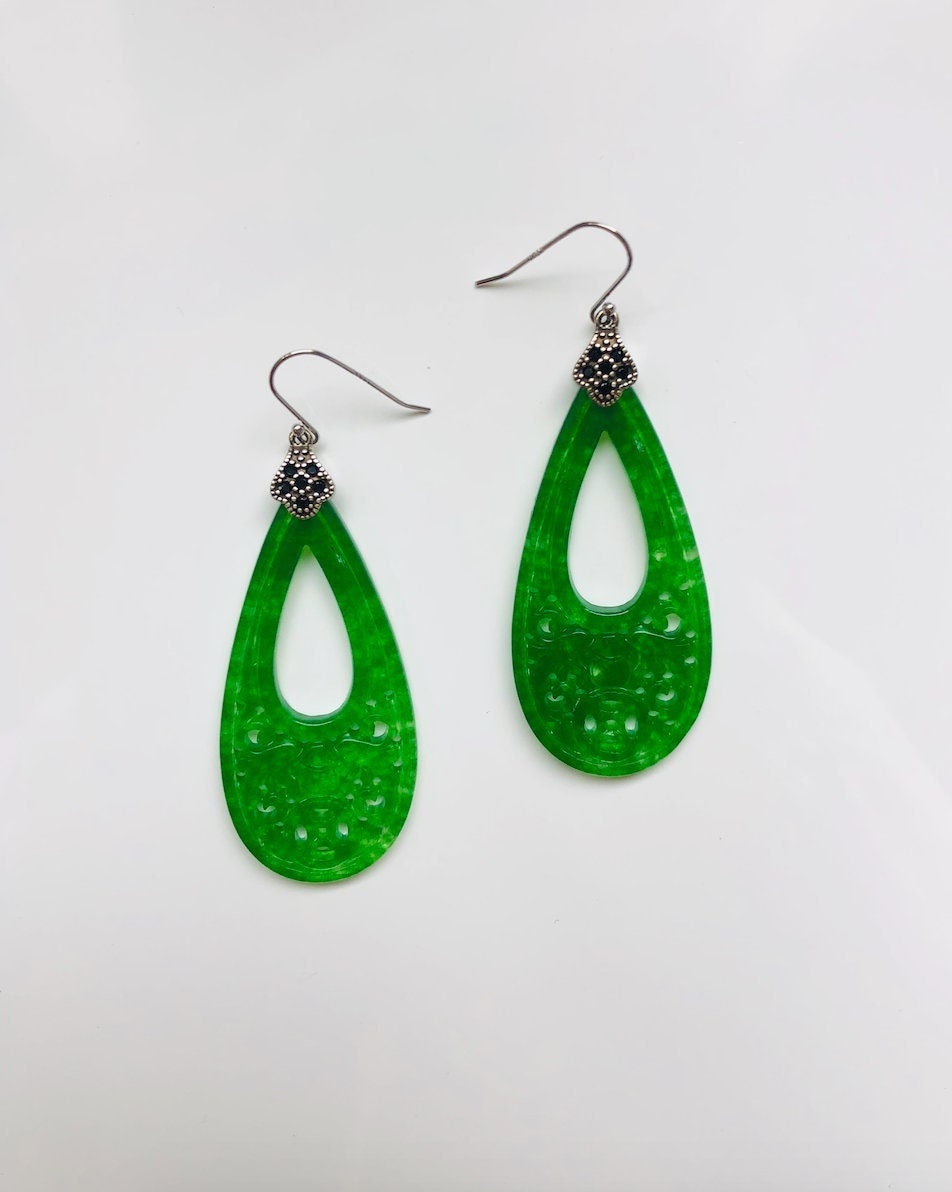A pair of long teardrop-shaped green jade earrings with vintage sterling silver hooks.
