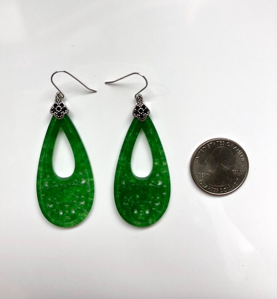 Green jade teardrop earrings shown next to a coin for scale reference
