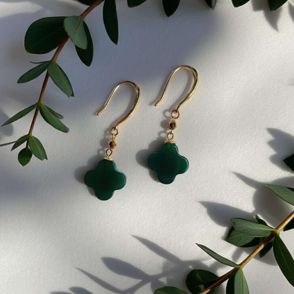 Front view of 18k gold clover earrings with dark green jade dangle surrounded by leaves