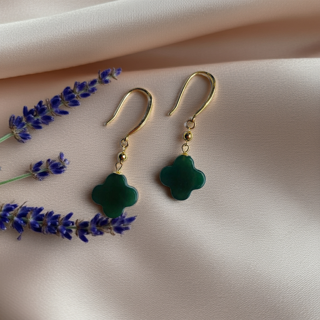 Clover-shaped green jade earrings on a soft silk fabric with lavender decorations