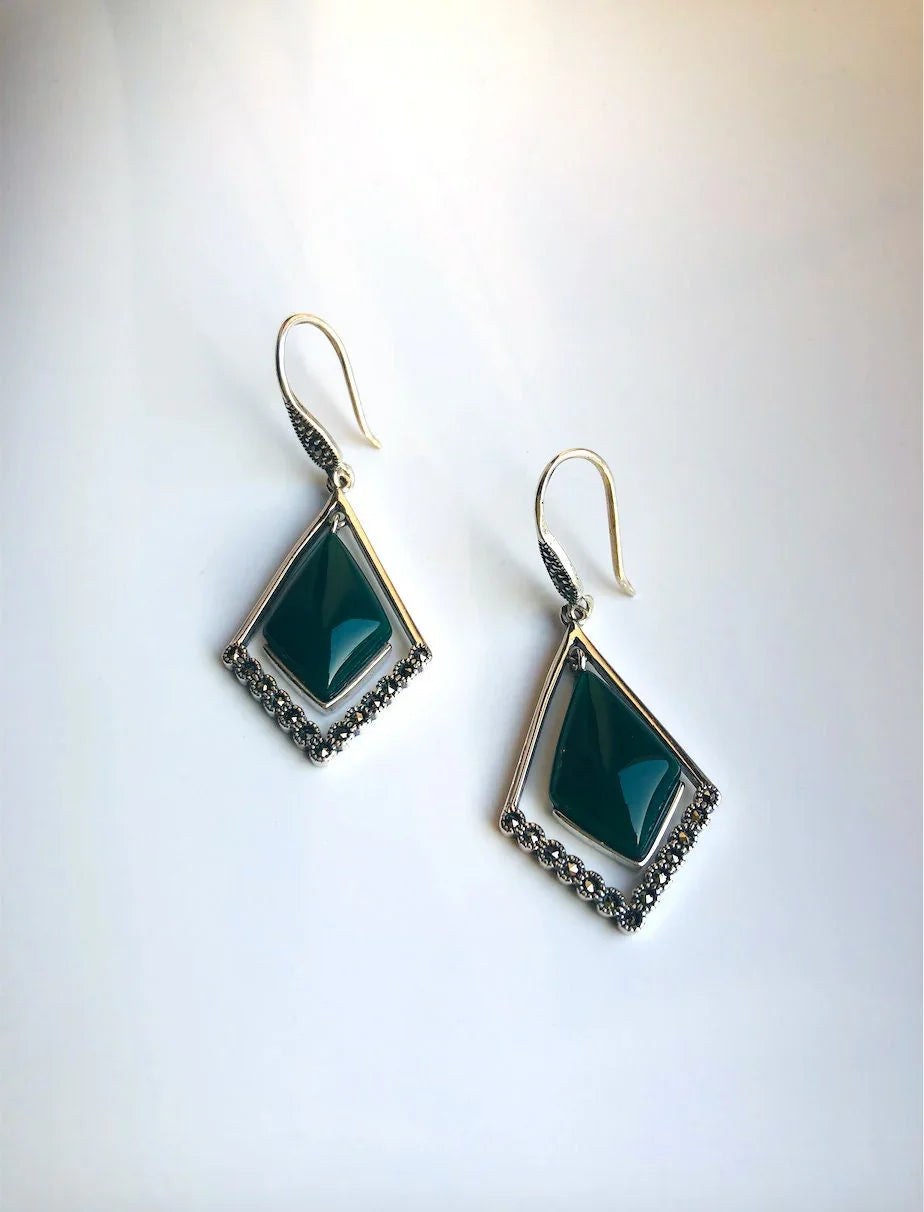Close-up of dark green jade earrings with antique-style silver hoop and carved edges