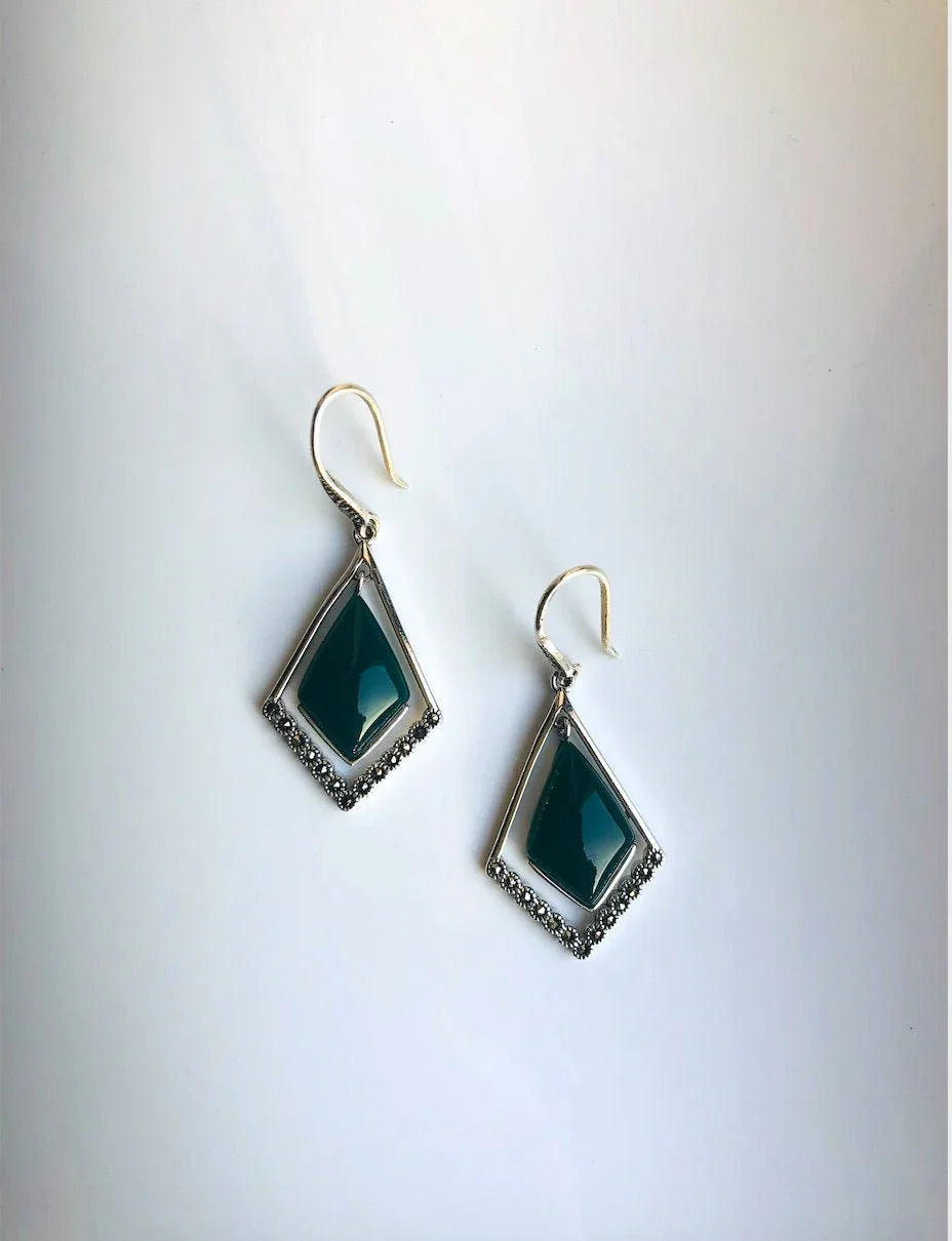 A pair of vintage dark green jade earrings with rhombus shapes and antique sterling silver hooks, displayed against a white background.