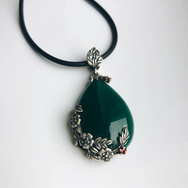Side view of dark green jade pendant showing floral silver detailing

