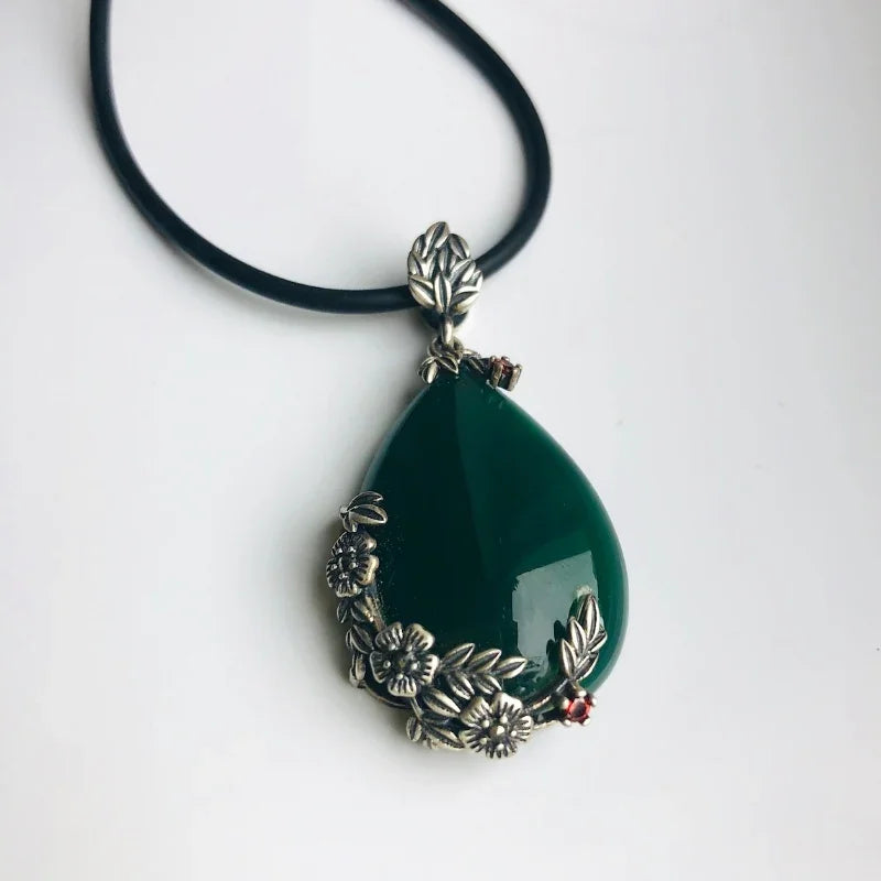 Side view of dark green jade pendant showing floral silver detailing

