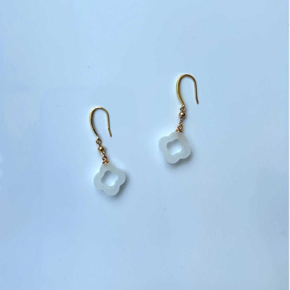 Side angle of gold and white jade clover earrings showing hanging drop shape and fine detailing