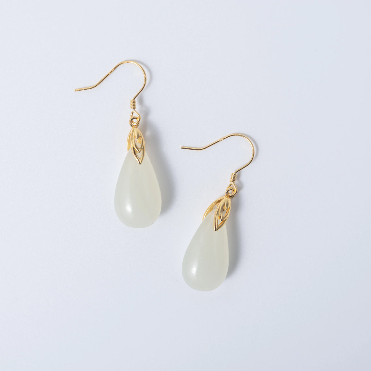 Modern white jade drop earrings in sleek gold design with teardrop silhouette on a white background