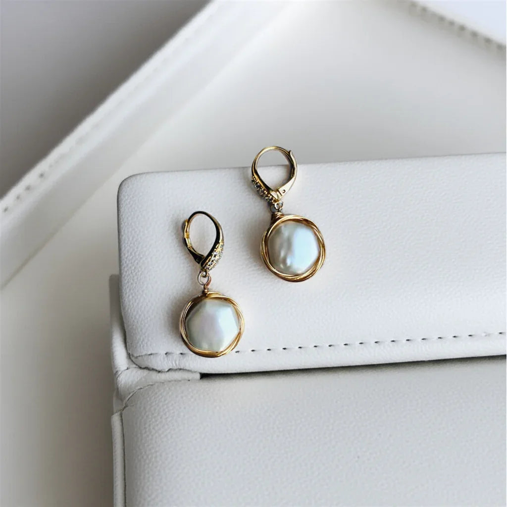 gold pearl drop earrings on a leather background