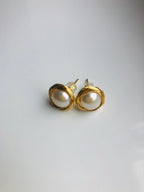 gold pearl stud earrings on a white backgrounf