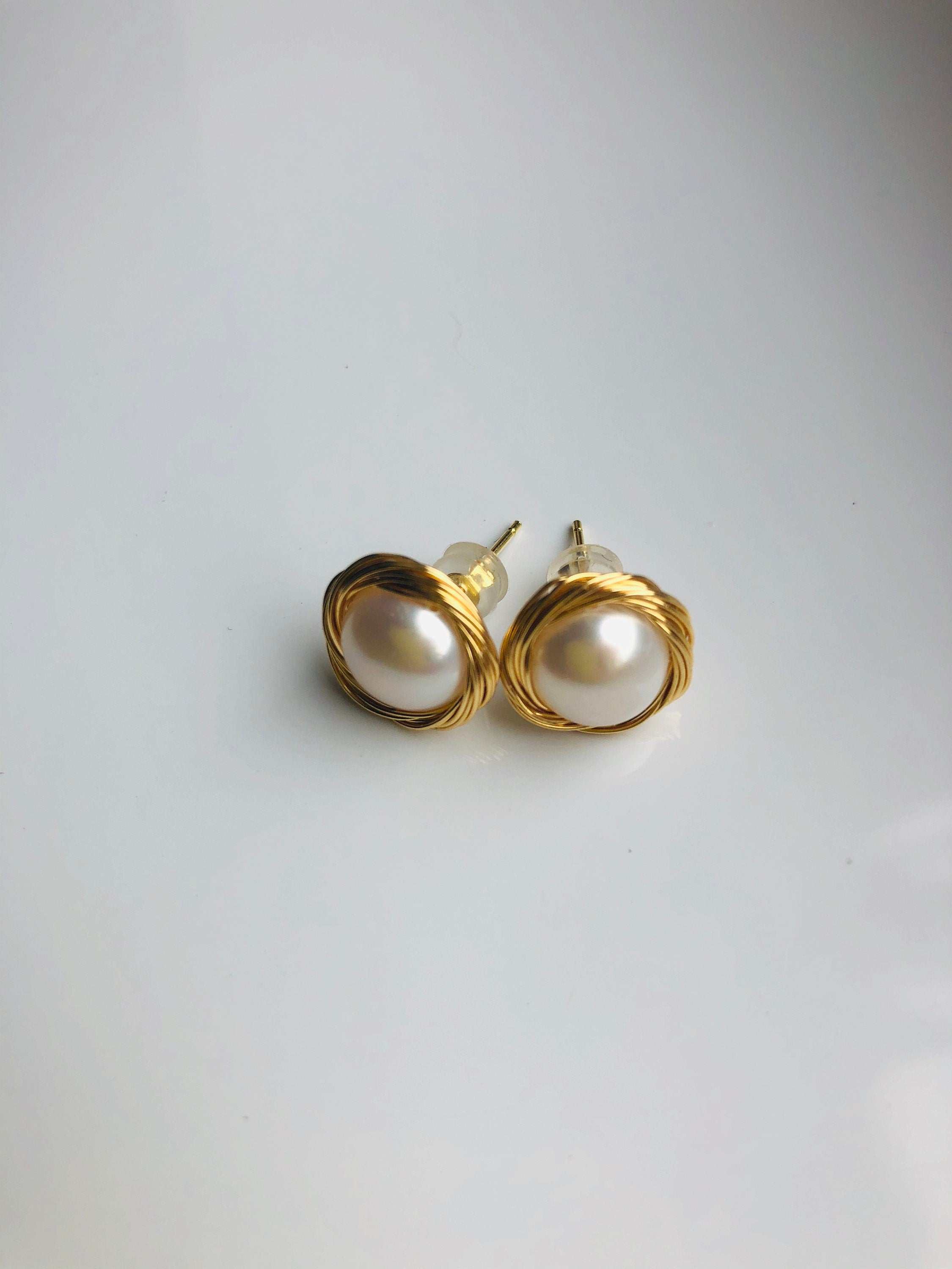 gold pearl stud earrings on a white backgrounf