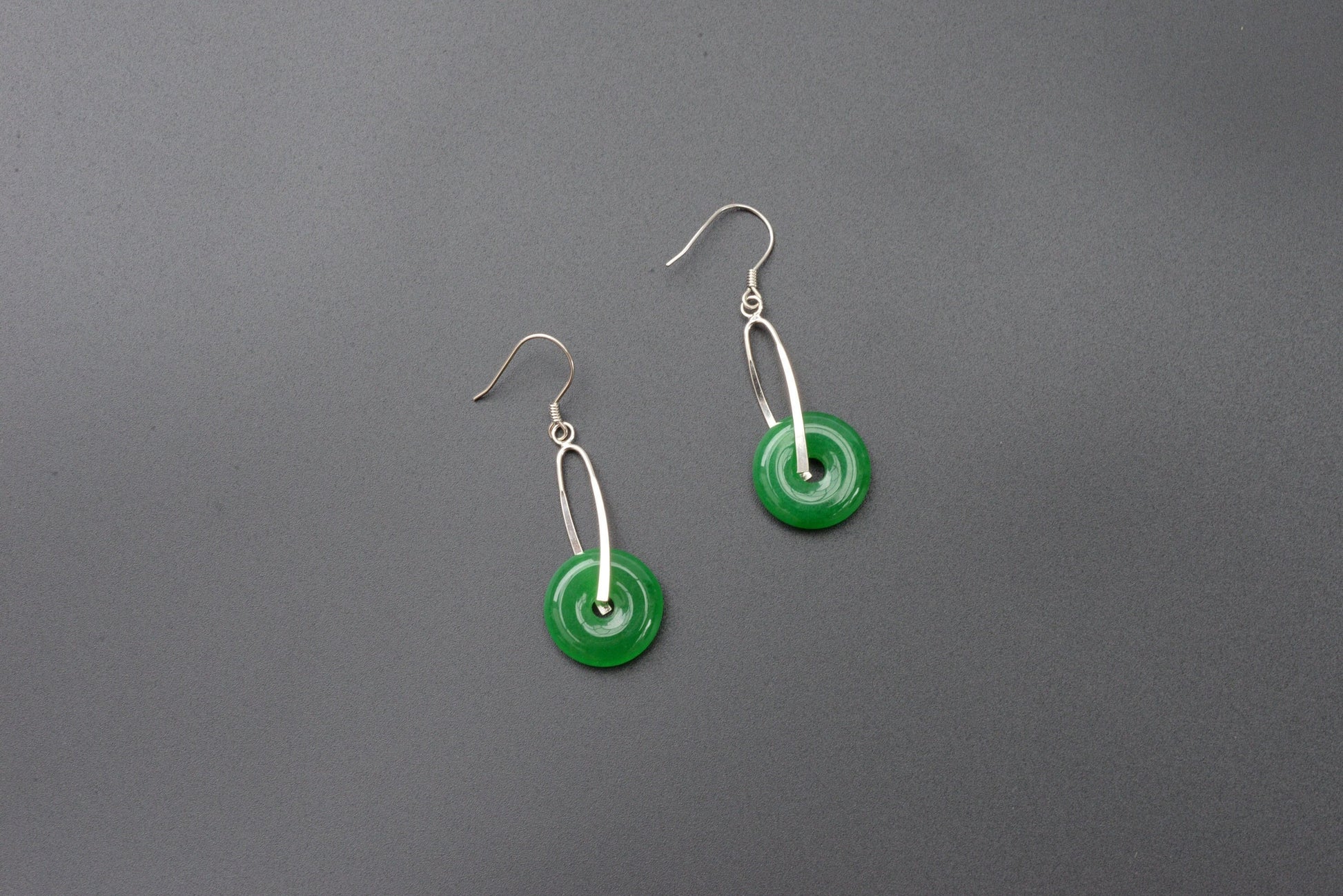 Front view of green jade donut earrings with sterling silver hooks and polished finish