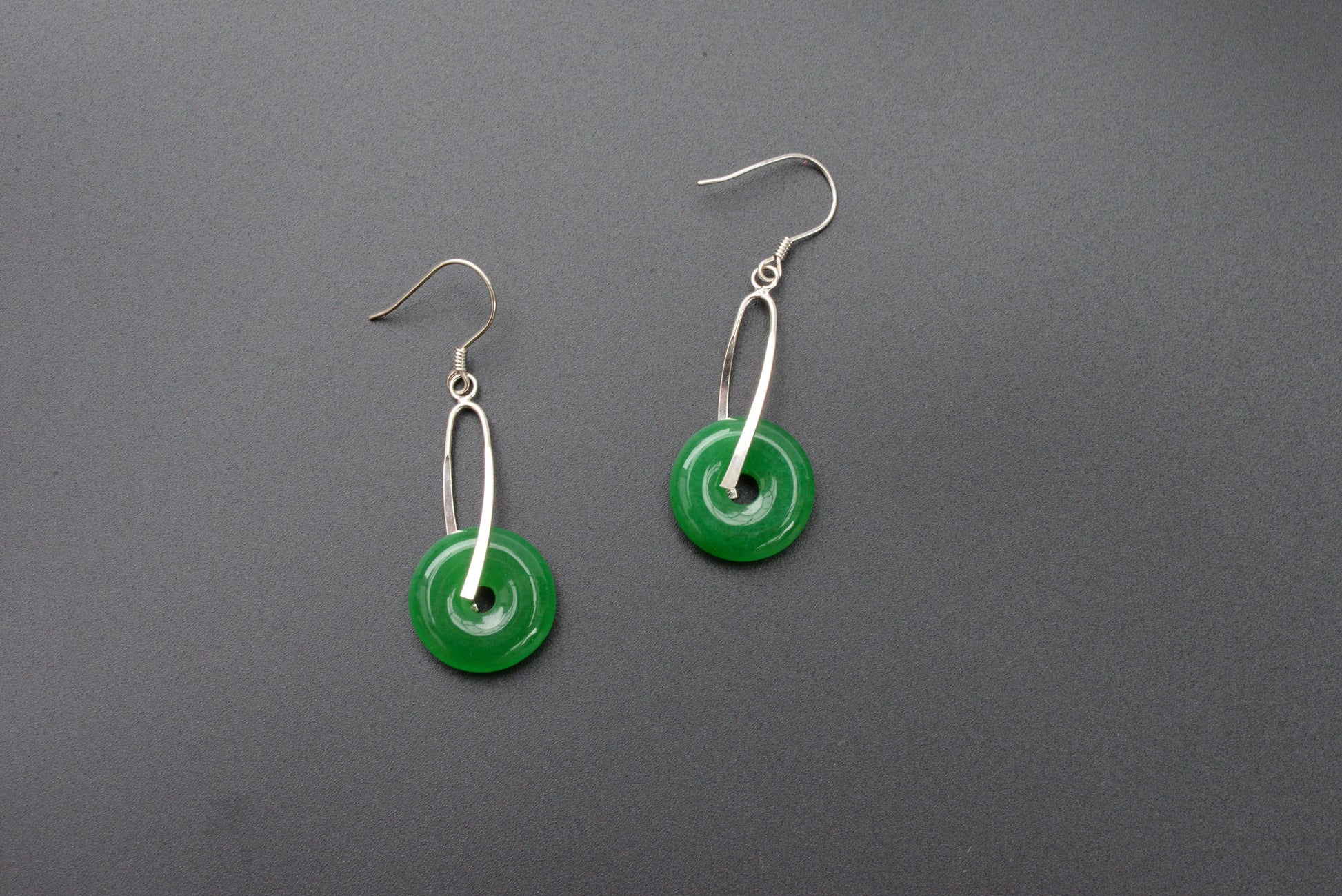 Front view of green jade donut earrings with sterling silver hooks and polished finish