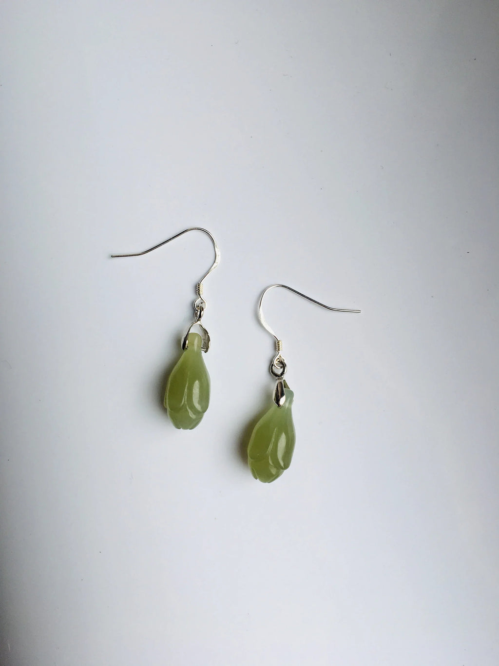 Pair of green teardrop earrings on a white background