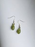 Pair of green teardrop earrings on a white background