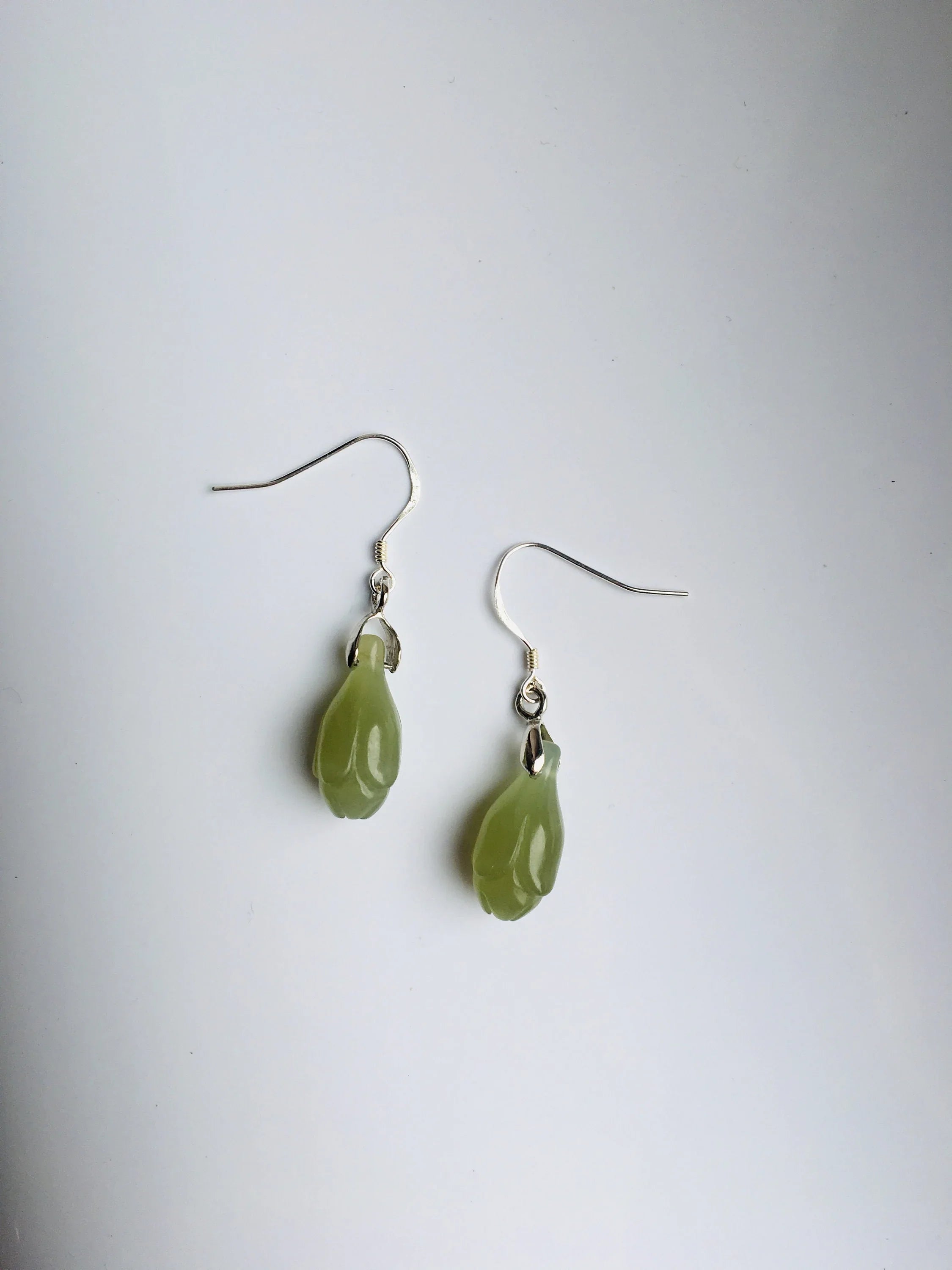 Pair of green teardrop earrings on a white background