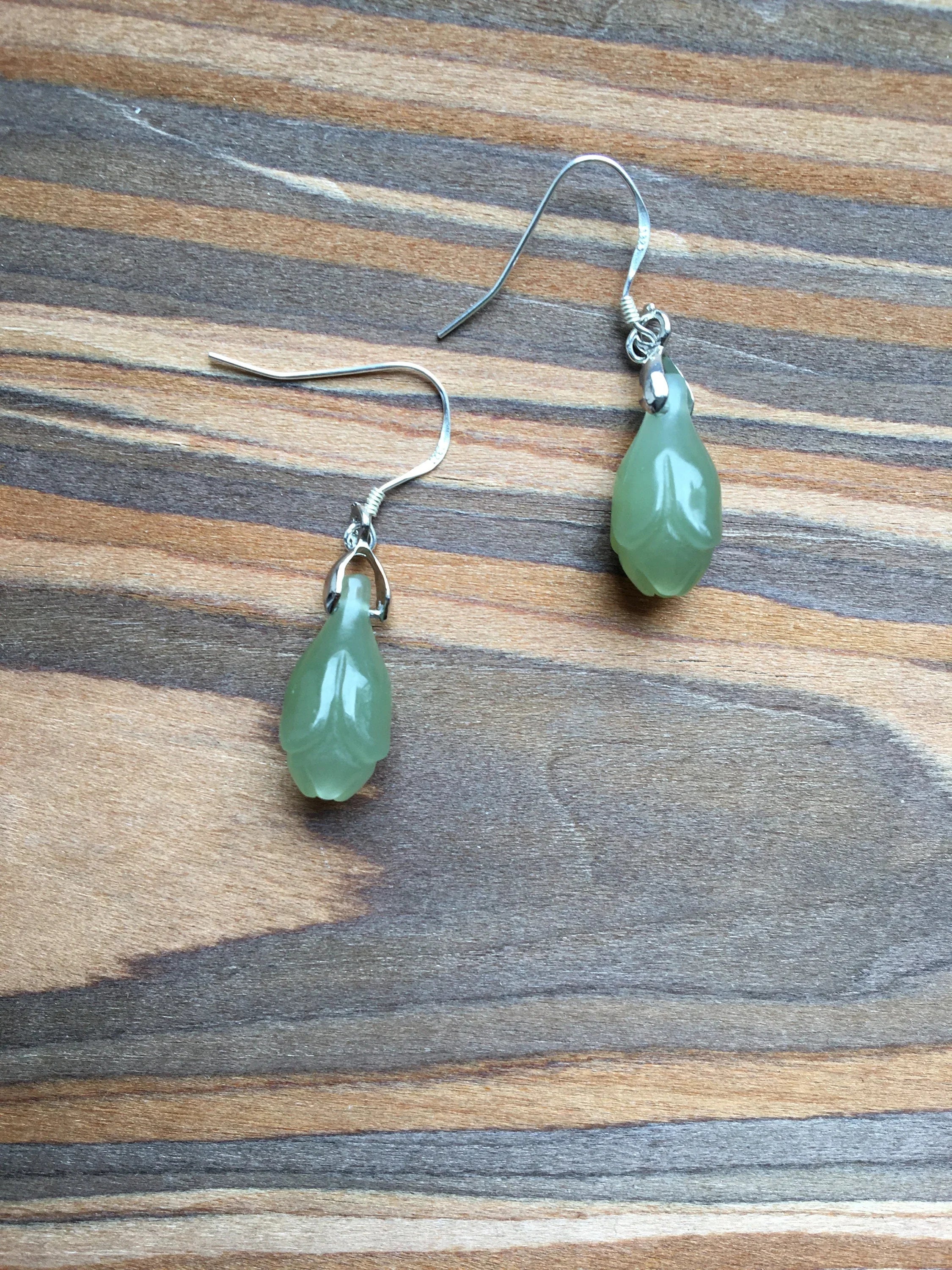 Green teardrop earrings on a wooden surface