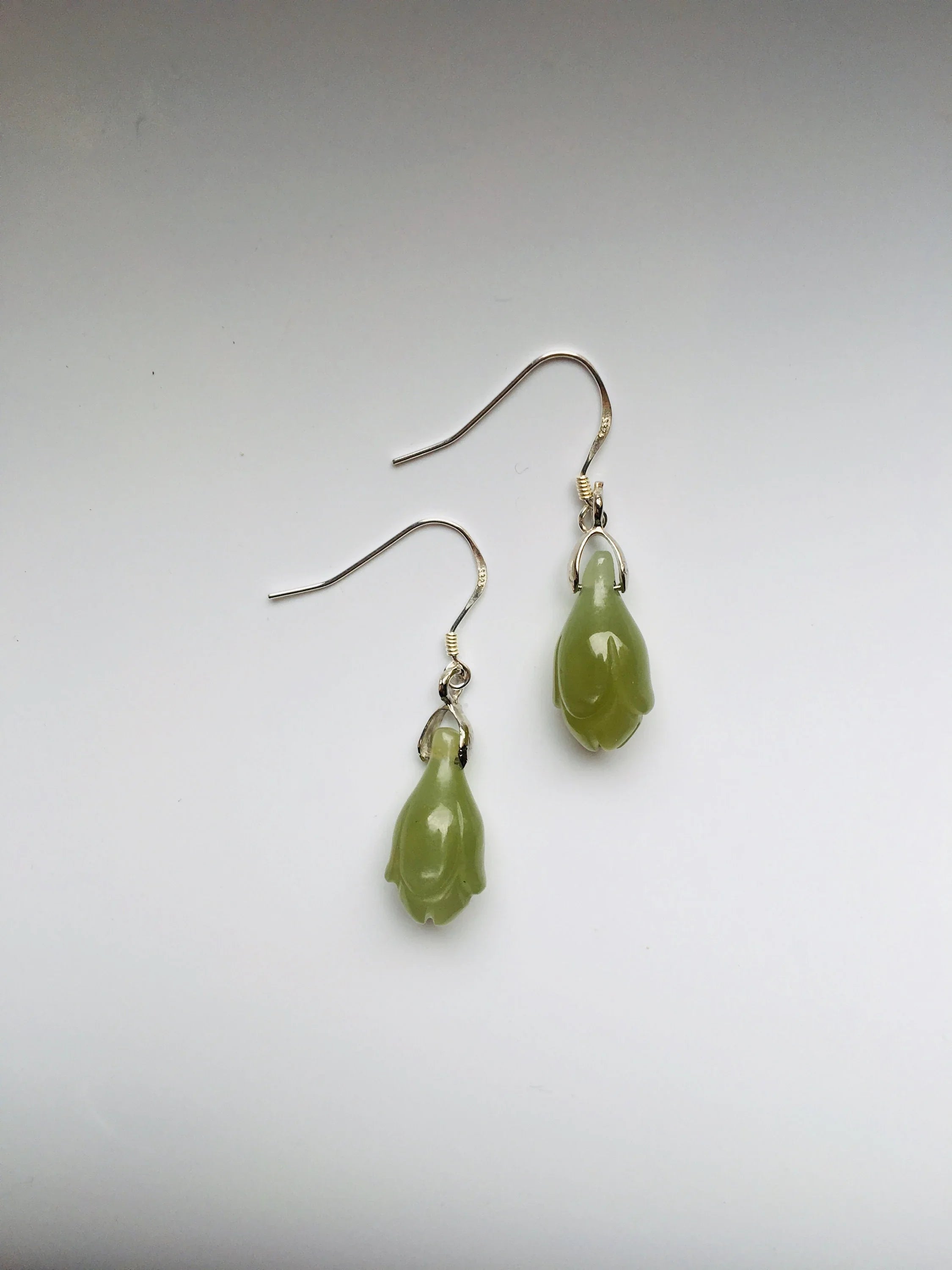Pair of green teardrop earrings on a light gray background