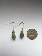 Green teardrop earrings next to a quarter on a white background