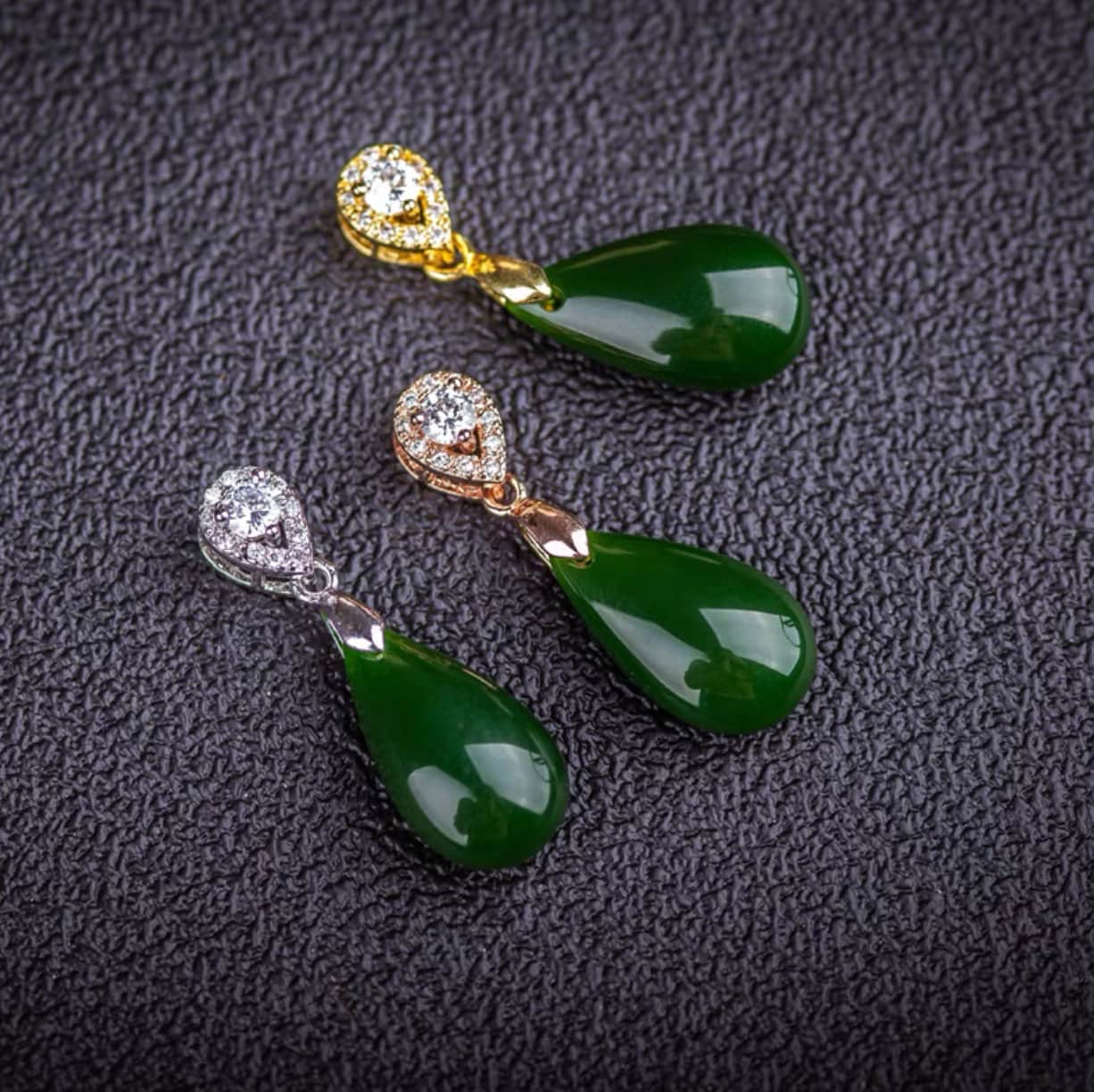 Close-up of natural green jade stone in teardrop shape with silver, rose gold and gold mounting