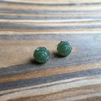 Front view of green jade rose stud earrings on woodgrain background