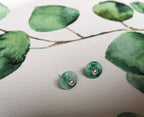 Green jade earrings on a white surface with green leaf pattern