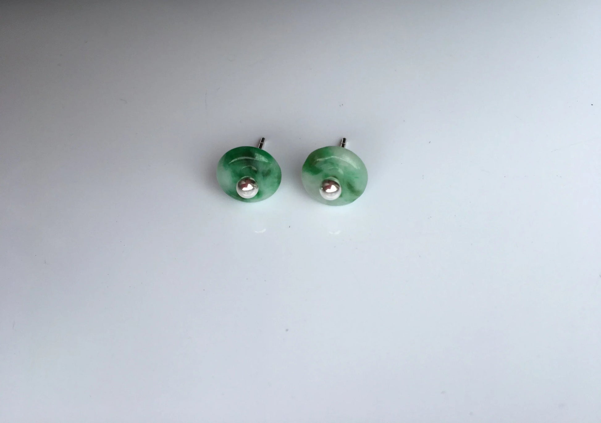 Side angle of tiny jade stud earrings showing gemstone depth and silver posts