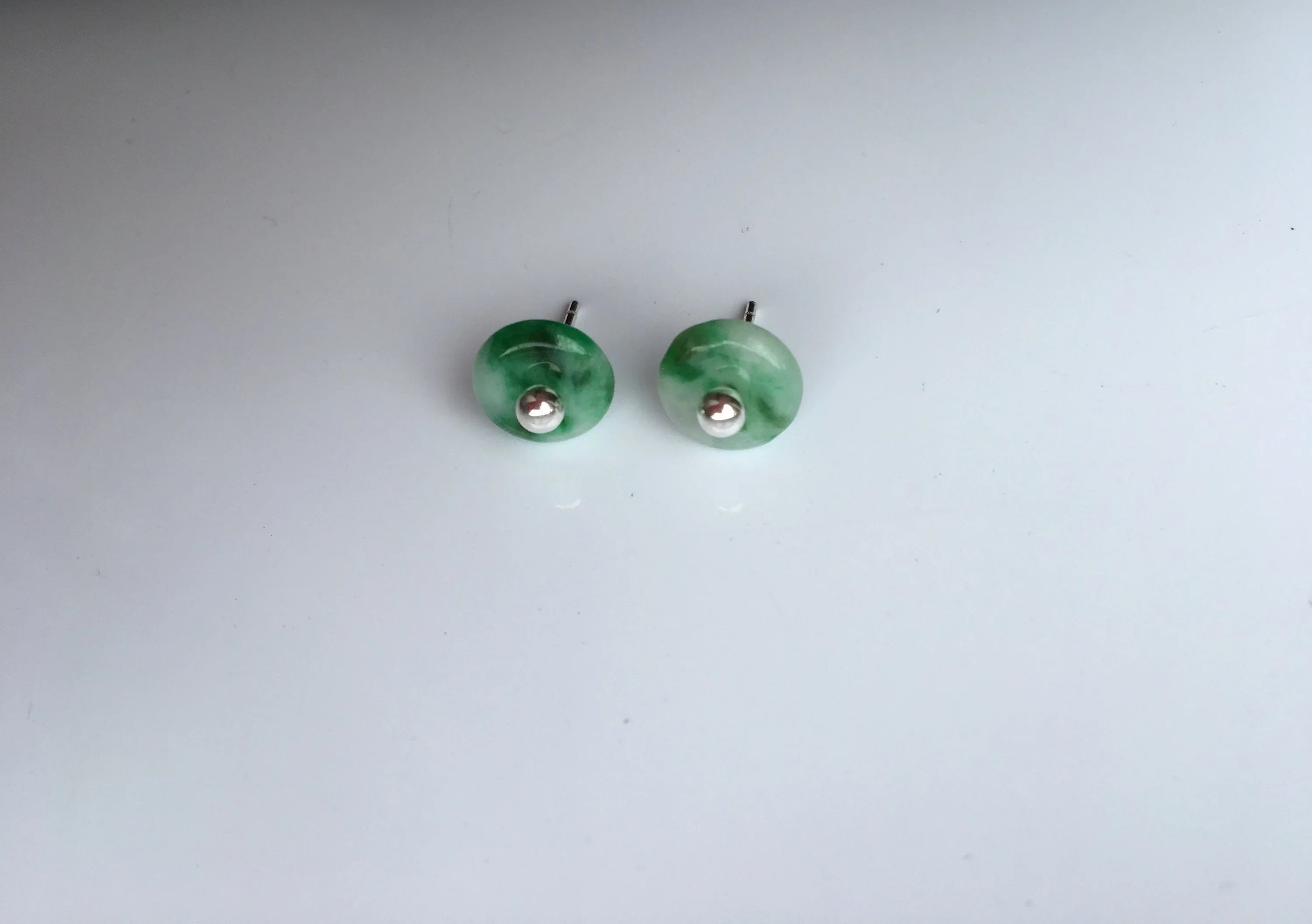Side angle of tiny jade stud earrings showing gemstone depth and silver posts