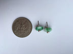 Green earrings next to a quarter on a white background