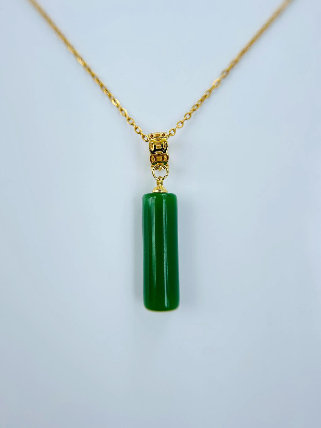 Close-up of green jade tube pendant with polished finish and gold cap detail