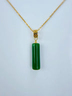 Close-up of green jade tube pendant with polished finish and gold cap detail