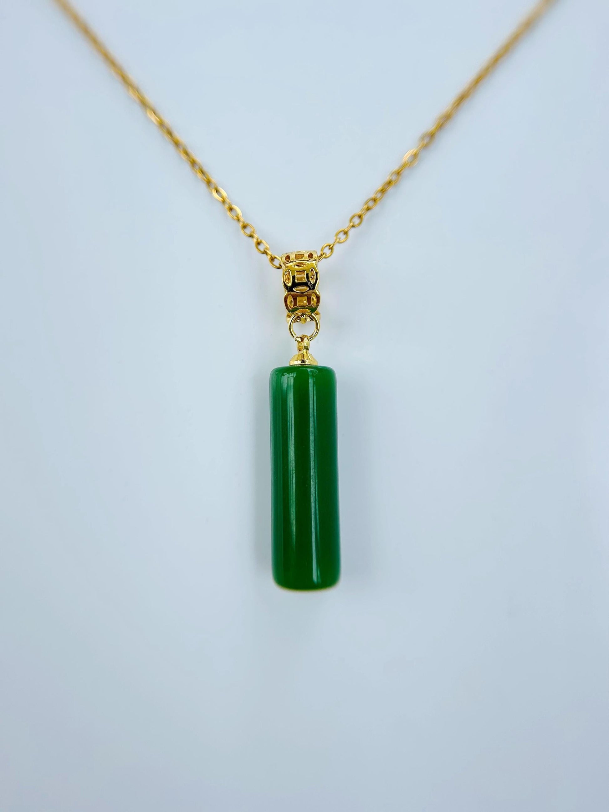 Close-up of green jade tube pendant with polished finish and gold cap detail