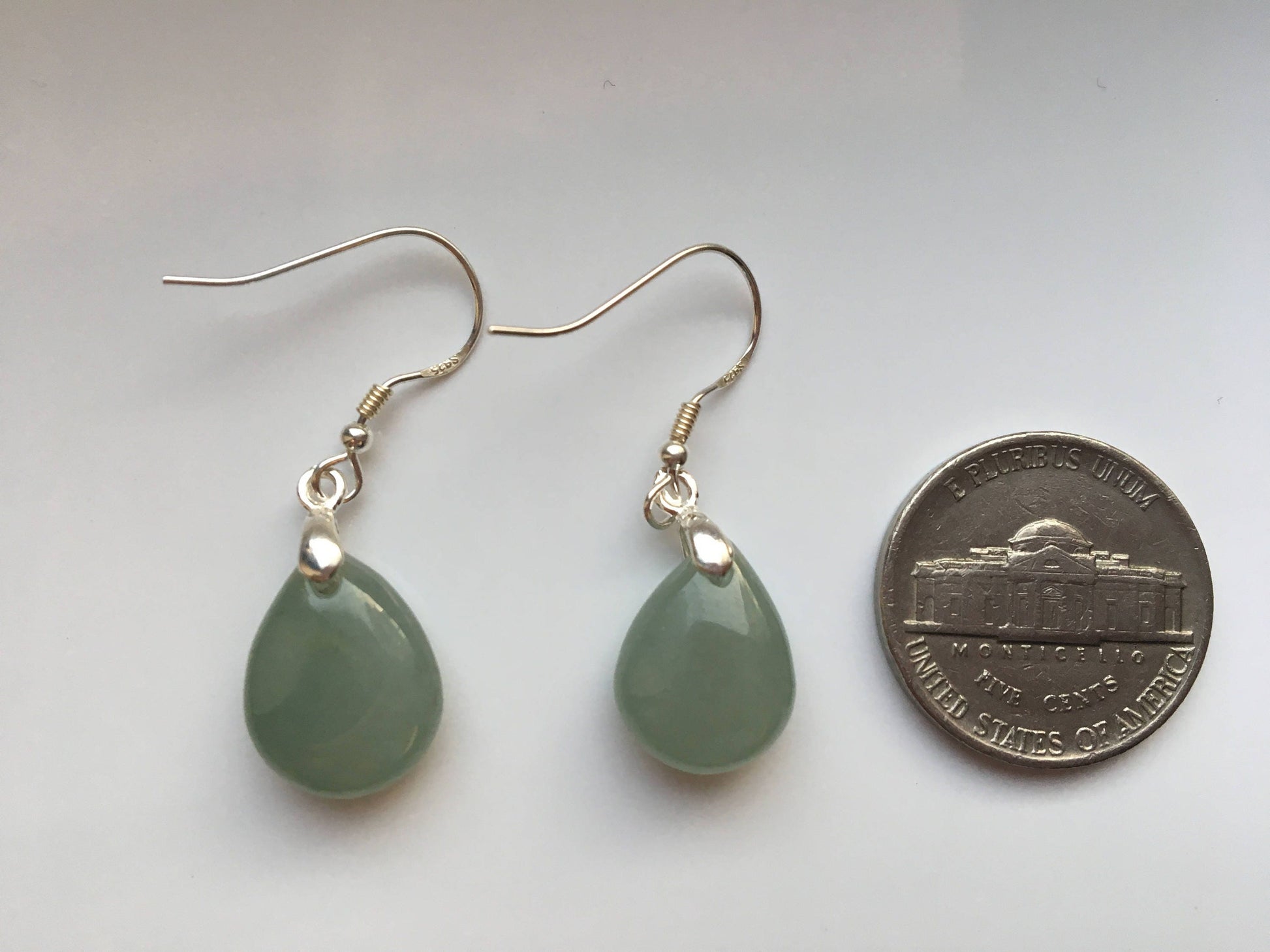 the green jade earrings compare with a coin for size reference