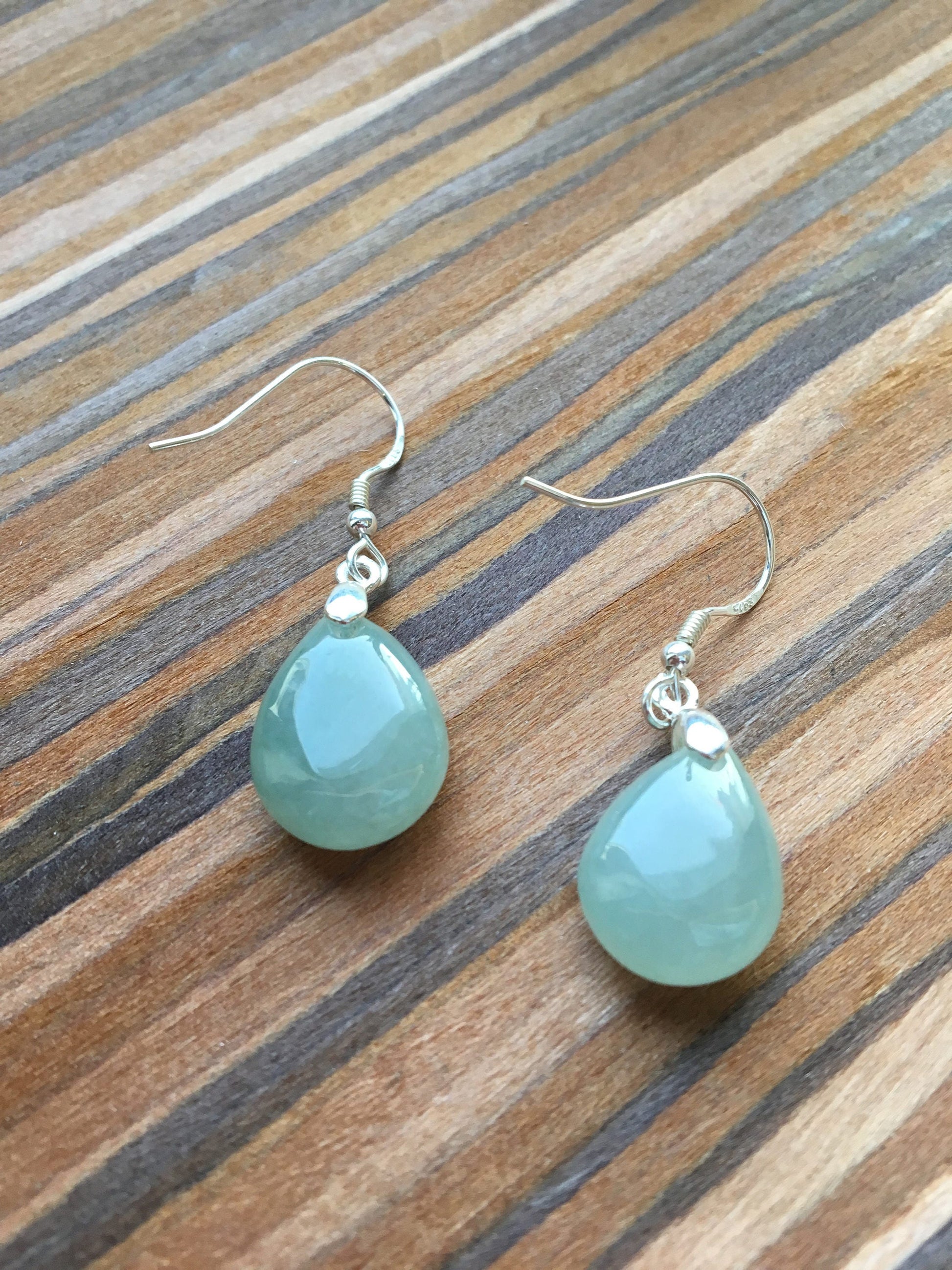 a pair of green jade jewelry against wooden background