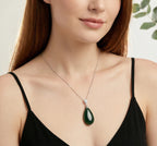 Woman wearing a necklace with a green pendant against a neutral background