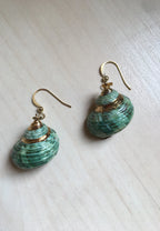 Pair of green shell earrings with gold accents on a light wooden surface