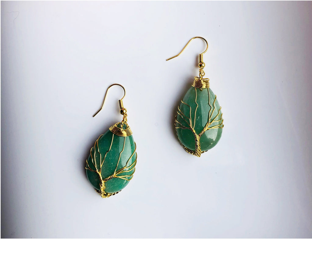 A pair of teardrop-shaped green jade earrings with gold wire wrapped around them, designed to represent a tree of life pattern.