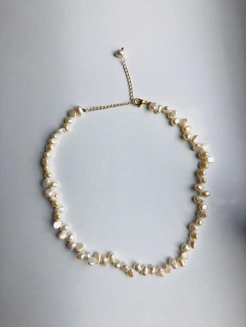 An irregular natural pearl necklace with gold-filled pearl beads. The necklace is white and gold in color, with an adjustable chain.