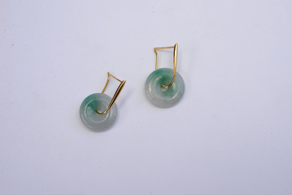 A pair of gold hanging jade donut earrings with a green and white color scheme against a white background.