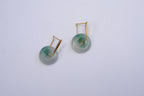 A pair of gold hanging jade donut earrings with a green and white color scheme against a white background.
