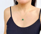 A person wearing a black tank top showcasing a green jade bead pendant necklace with gold-plated chain.